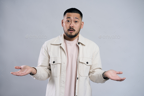 Portrait of confused asian bearded man looking at camera with answer