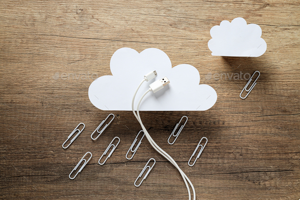 White paper clouds with white USB cable and metal paper clips on wooden background