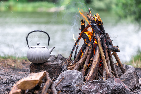 Campfire kettle closeup with blurred bonfire in the background