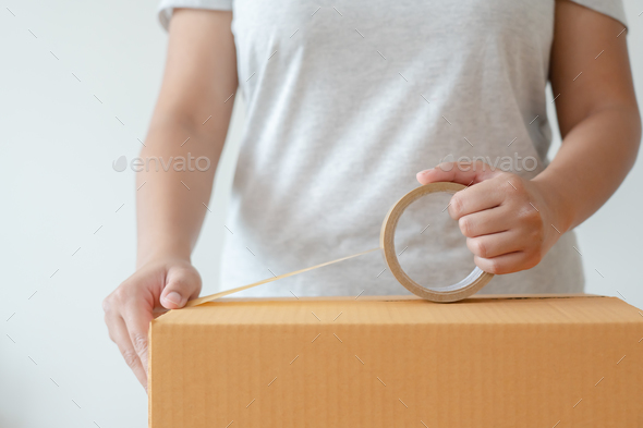 Woman sealing tape cardboard box preparing to delivery