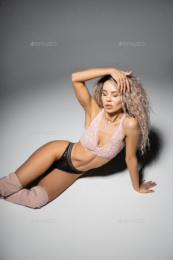 fashion and femininity, sexy woman with toned body and wavy ash blonde hair  posing in lace bra Stock Photo by LightFieldStudios