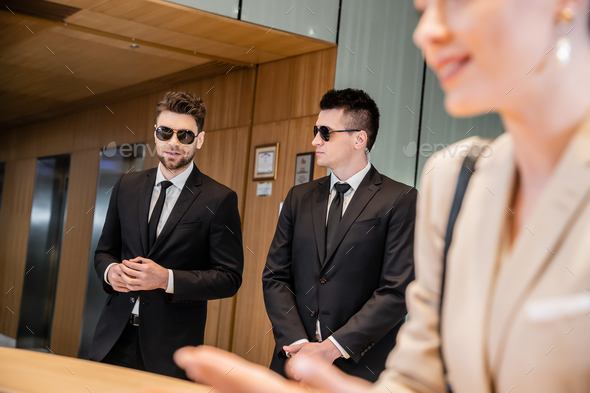 handsome bodyguards protecting successful client in hotel, woman on blurred foreground, security