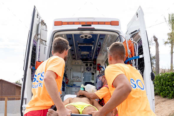 Lifeguards transporting a patient with the stretcher inside the ambulance