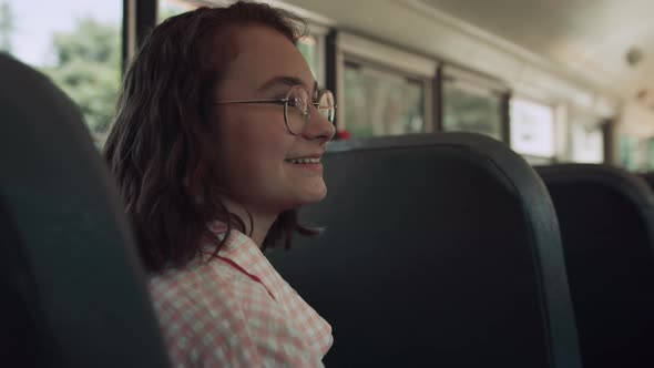 Smiling Teen Girl Sitting School Bus Talking with Friends alt