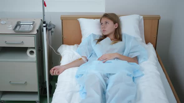 Portrait of Depressed Teenage Caucasian Girl Lying in Hospital Ward with Dropper Thinking alt