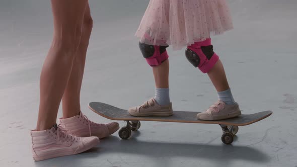 Unrecognizable Woman Teaching Daughter Skateboarding alt
