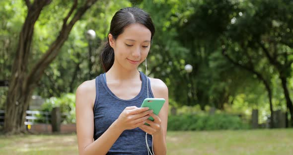 Sport Woman Listen to Music on Cellphone with Earphone in The Park alt