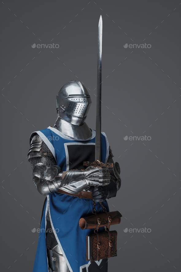 Medieval guard dressed in armor and blue surcoat holding a sword