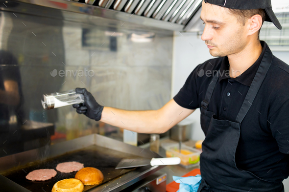 The chef in kitchen of the restaurant makes cutlets for burgers - smash burger beefsteak