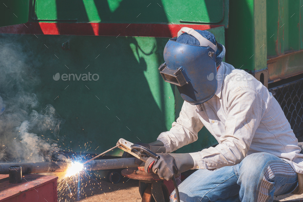Welder welding galvanized steel pipe for improvement building structure in construction site area