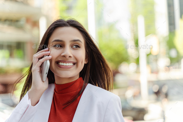 Cheerful confident Indian woman answering call looking away