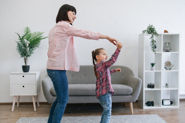Mother whirling tween kid to upbeat tunes in living room