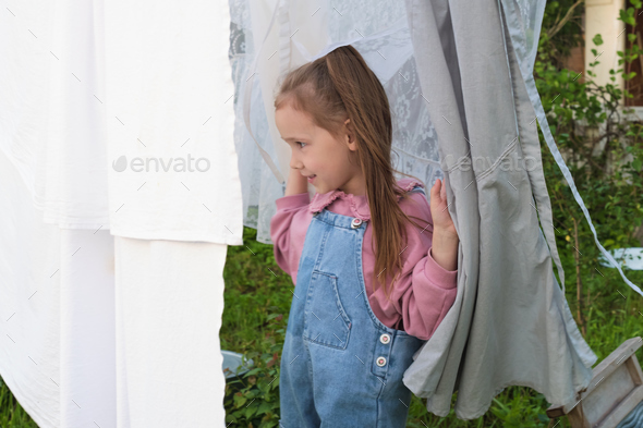 Emphasizing sustainable clothing choices, a young girl sports a denim jumpsuit, playing amidst the