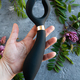 A black toy for adults in a woman&#39;s hand. The background is concrete with flowers. - PhotoDune Item for Sale