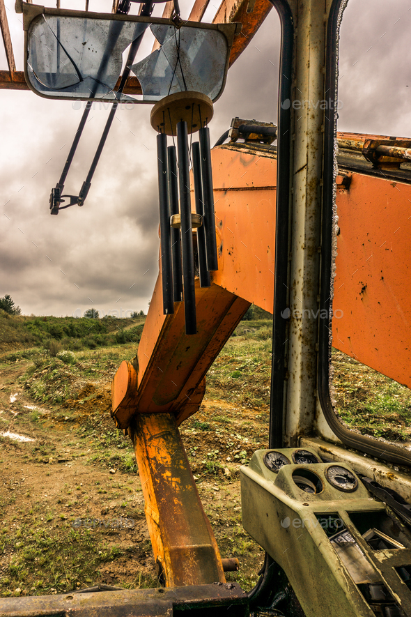 inside of abandoned orange excavator driver cabine with cloudy sky