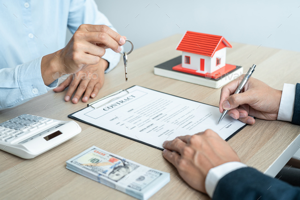 Real estate broker agent holding filing keys to the customer after signing rental lease contract