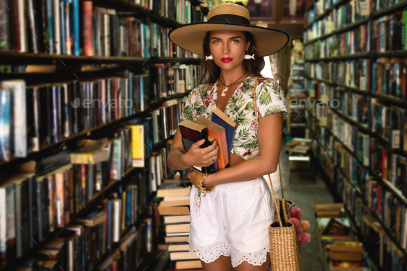 Beautiful girl wearing stylish outfit looking for interesting book in the vintage bookstore
