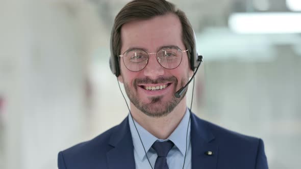 Portrait of Young Businessman with Headset Smiling at the Camera  alt