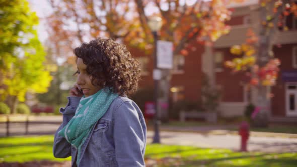 College student on campus in fall talking on cell phone