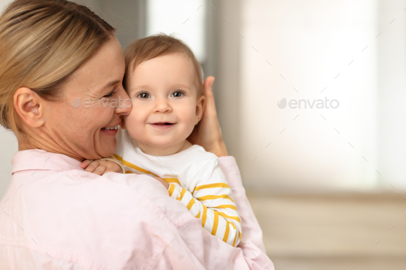 Joy of motherhood. Loving mother rubbing nose on baby daughter\'s cheek, embracing pretty little