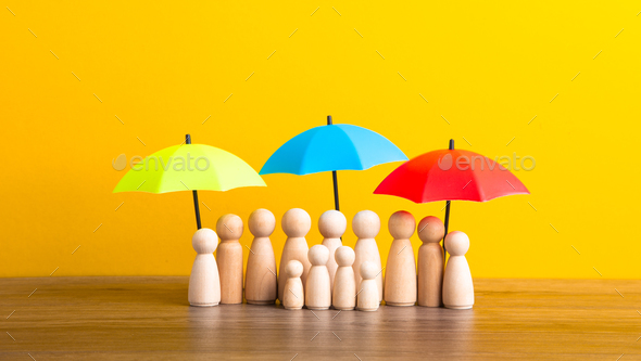 Many wooden people figures under umbrella on yellow background.
