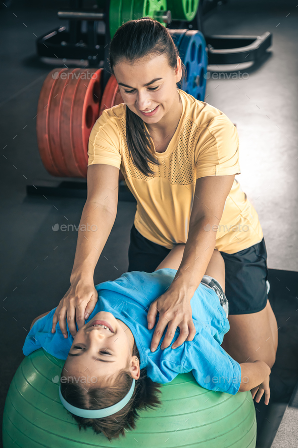 Cute child girl stretching on pilates fitness ball with mom in gym. Stock  Photo by puhimec