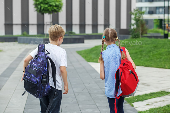 Back to school. Teenagers with backpacks go to school to study. Meeting friends