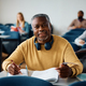 Smiling black mature man studying while attending adult education class and looking at camera. - PhotoDune Item for Sale