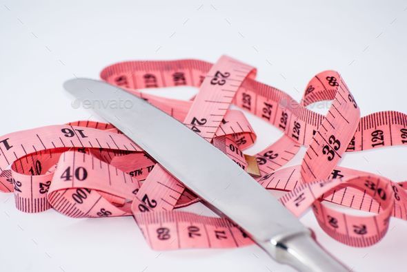 Closeup shot of a pink measuring tape and silverware- diet, weight loss  concept Stock Photo by wirestock