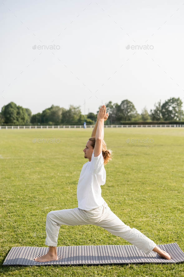side view of woman in bright clothes practicing yoga doing lunge exercise  standing in Warrior pose against the backdrop of rocky steps.  Virabhadrasana - Stock Image - Everypixel