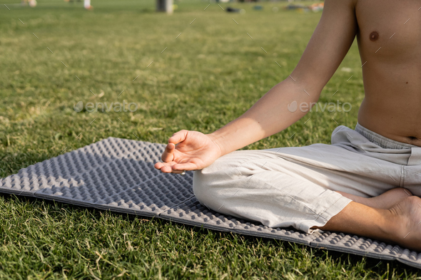 cropped view of shirtless man in linen pants showing gyan mudra gesture while meditating in easy