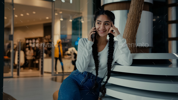 Young businesswoman student ethnic iranian arabian 20s woman girl shopper speak phone sit in