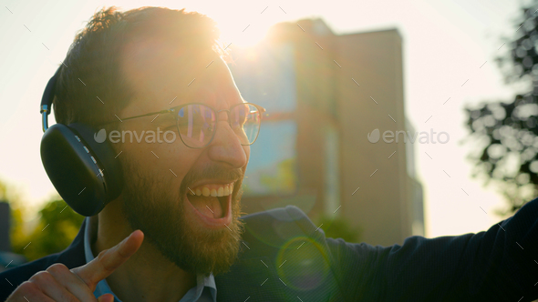 Excited Caucasian businessman listen song dance to music in headphones outside active happy business