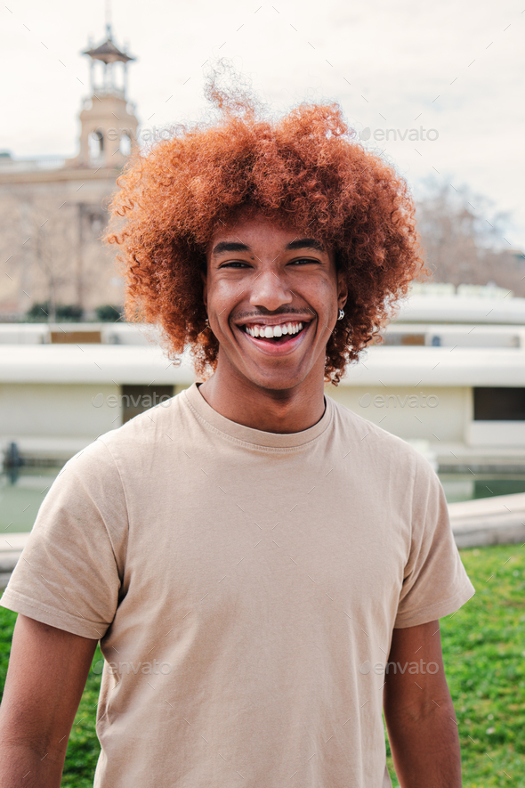 Individual portrait of one joyful african american guy with afro hair looking at camera with