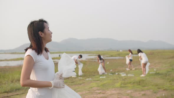 young Asia lady volunteers help to keep nature clean up, looking at camera.