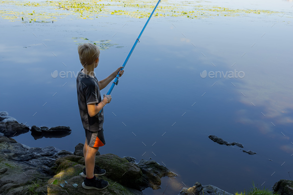 Kid with Fishing Rod at Lake. Little Boy Catching a Fish Stock