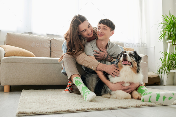 Young and carefree same sex couple in socks hugging and petting  