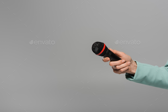 Cropped view of hand of host of event in blue jacket holding black and wireless microphone