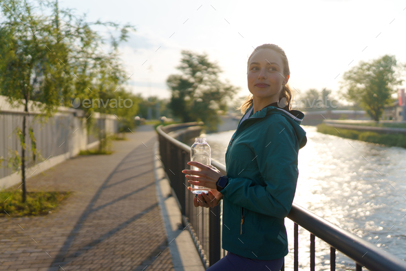 Attractive Sporty Young Woman Drinking from Blue Shaker Bottle in