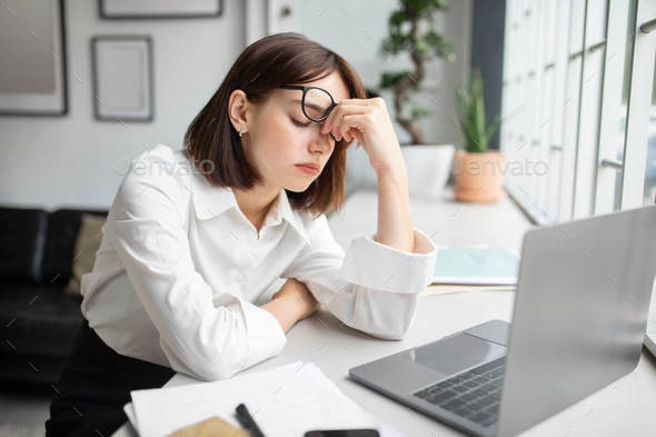 Eyes strain. Overworked businesswoman tired after using laptop, sitting in office, upset woman