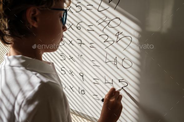 Diligent schoolboy near whiteboard during math lesson