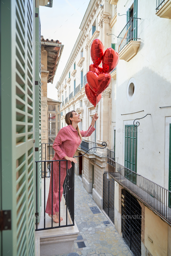 Lady on balcony pretending to launch heart balloons