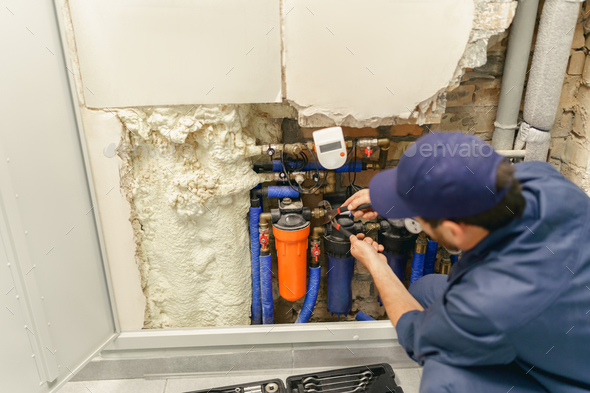 Back view of professional plumber repairing water supply system at home uses an adjustable wrench