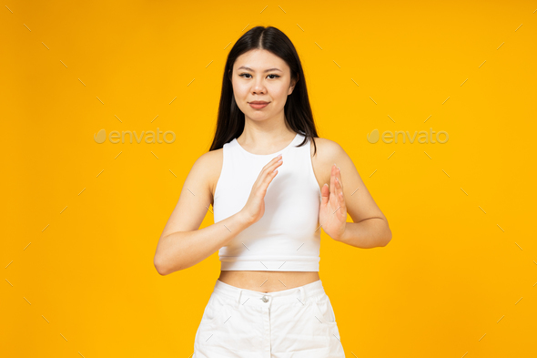 A girl of Asian appearance points with her hands to the chest area.