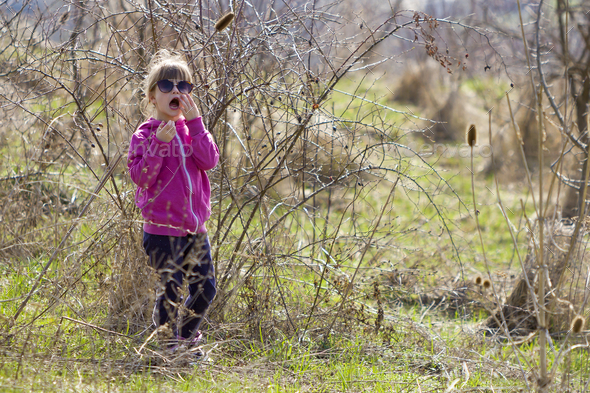 Portrait of cute small confused blond girl in casual pink clothing and dark  sunglasses Stock Photo by bilanol