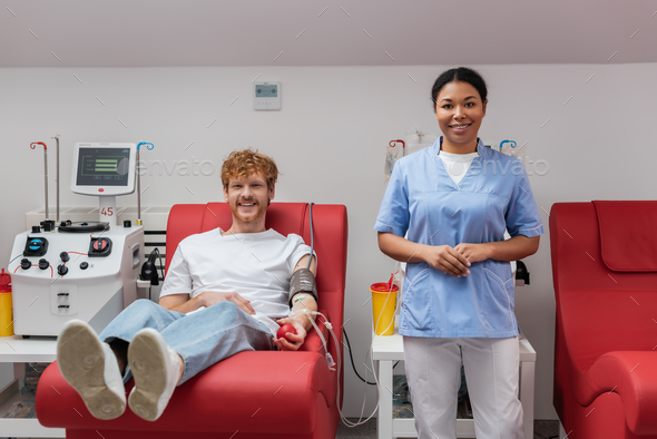 happy redhead man with blood pressure cuff and rubber ball sitting on medical chair