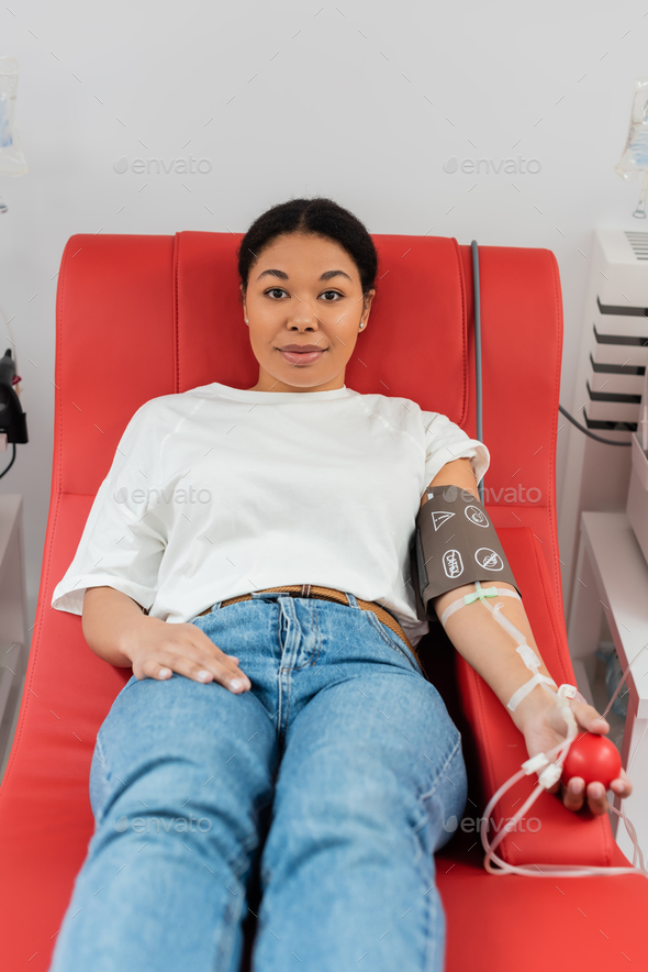 positive multiracial woman with pressure cuff, transfusion set and medical rubber ball sitting