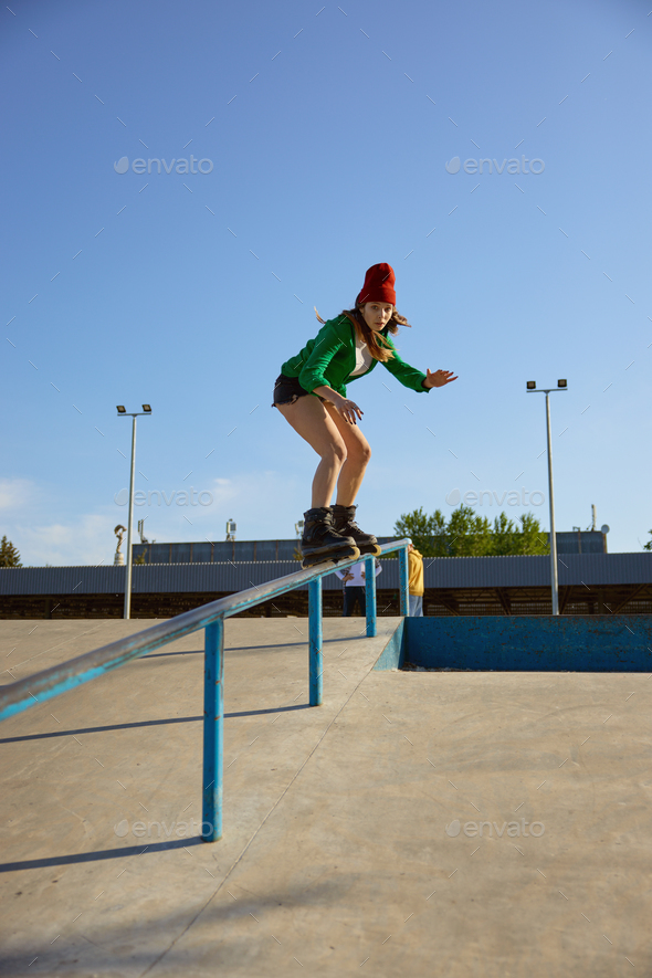 Cool young roller blader female grinding on a rail in a skatepark