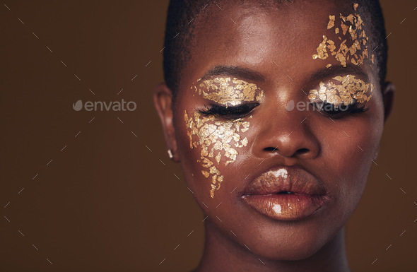 Gold, face and black woman with makeup for beauty aesthetics isolated in a studio brown background