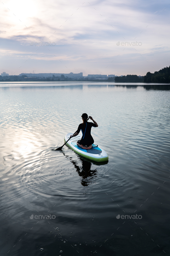Water sports, surf lessons. Stand on a kayak on the water with the warm colors of a summer sunset.